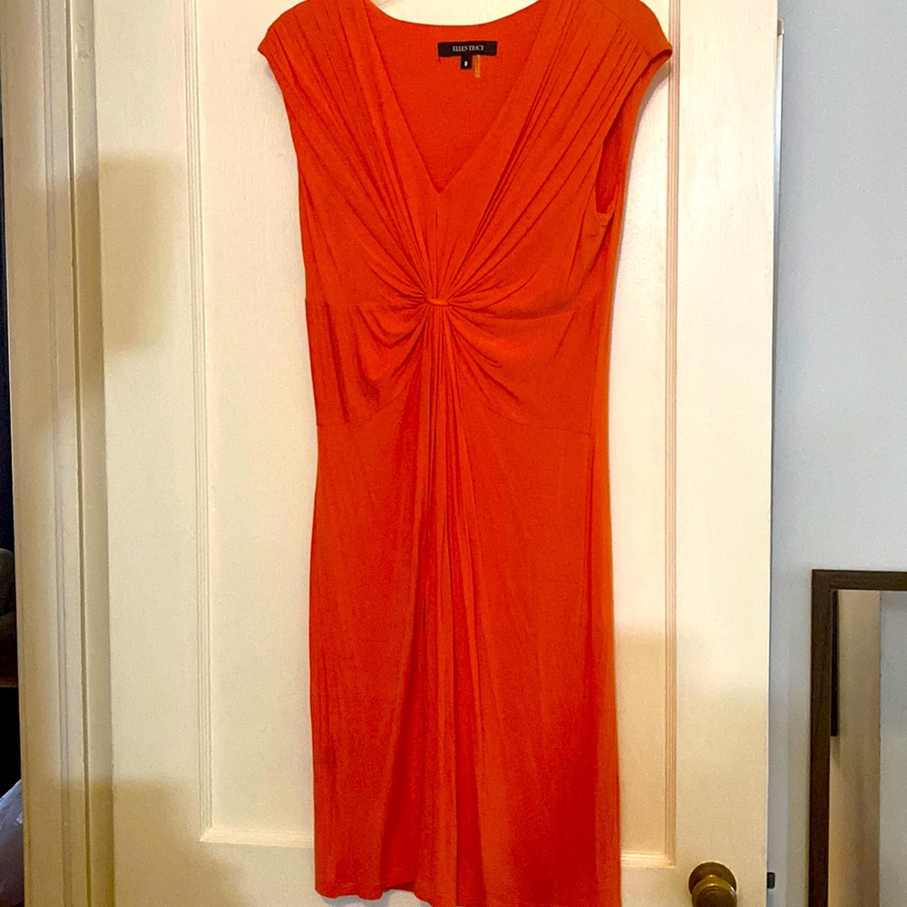 Slim fitting orange dress with v front. Sleeveless with pleated front.